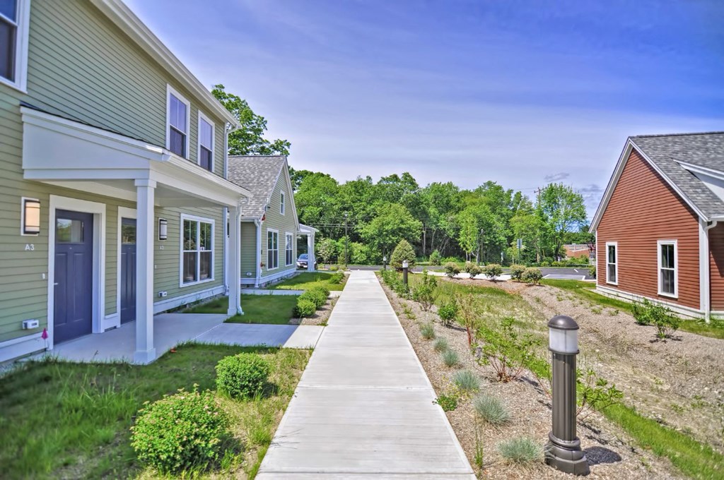 a row of houses with a sidewalk and grass