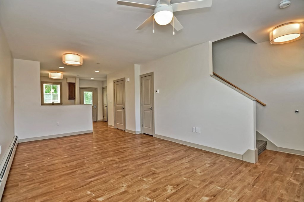 an empty living room with a ceiling fan and wood floors