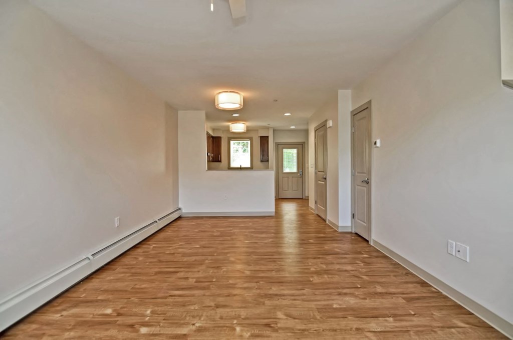 an empty living room and hallway with white walls and wood floors