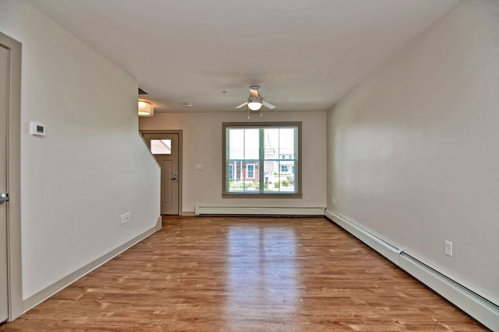 an empty living room with a window and a wood floor