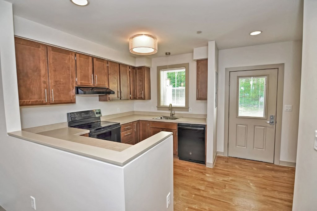an empty kitchen with wooden cabinets and a black stove