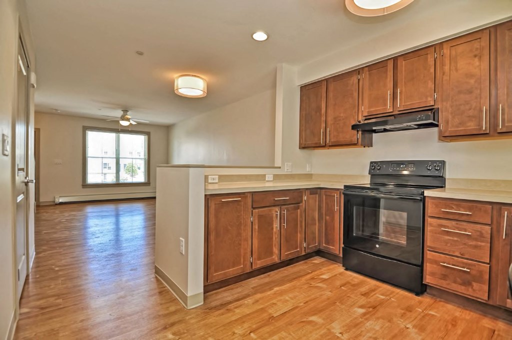 an empty kitchen with wooden cabinets and black appliances