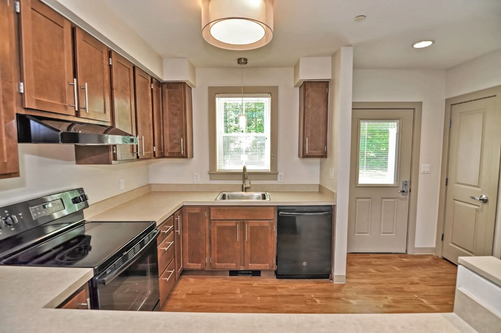 a kitchen with wooden cabinets and black appliances and a window