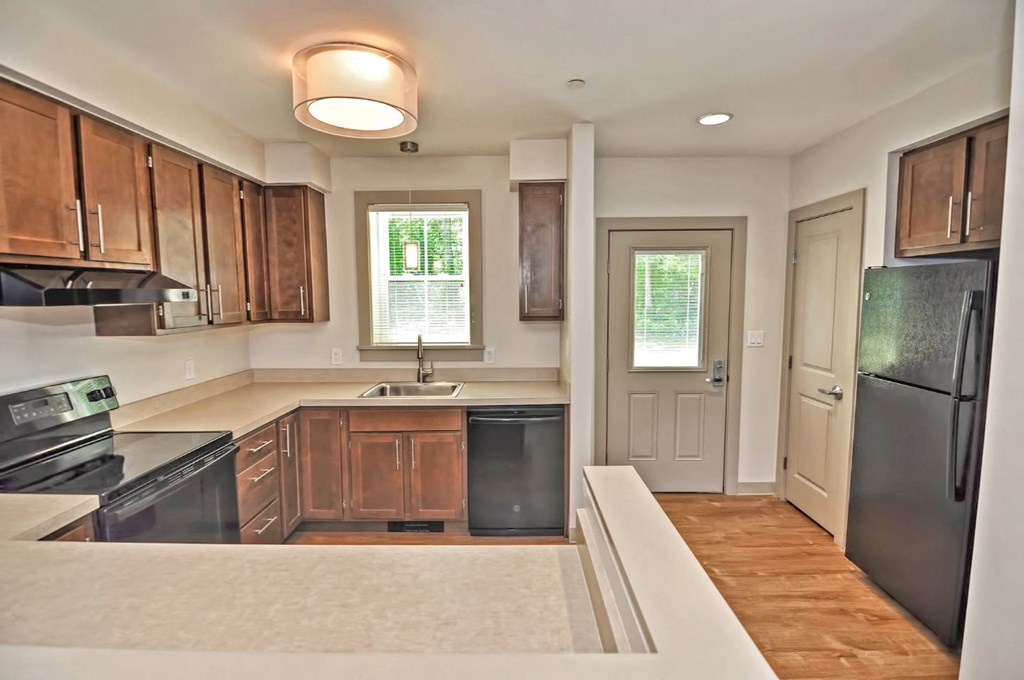 an empty kitchen with wooden cabinets and a black refrigerator
