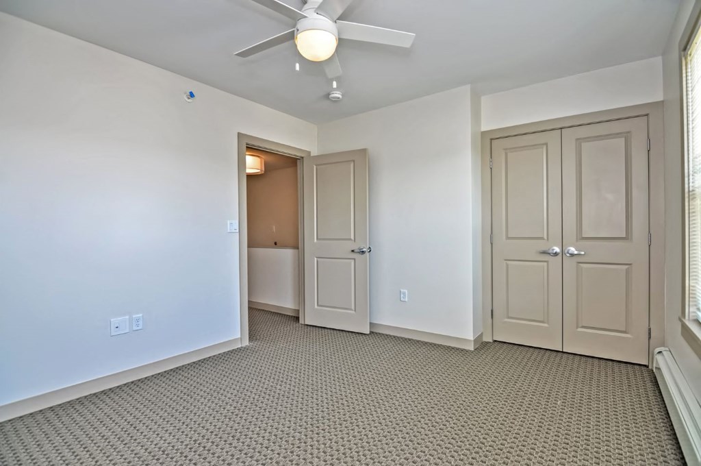 a living room with two doors and a ceiling fan