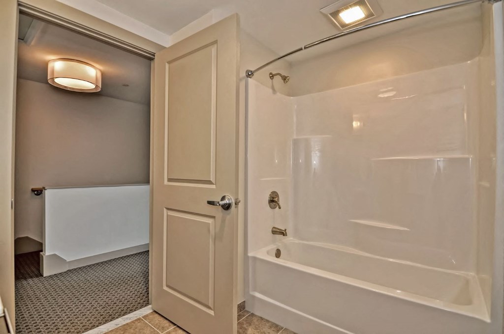 a bathroom with a shower and a tub and a door