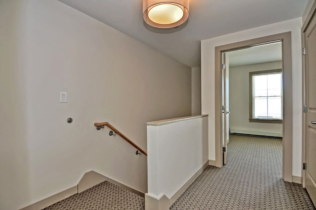 the landing of a staircase in a home with a door and a window