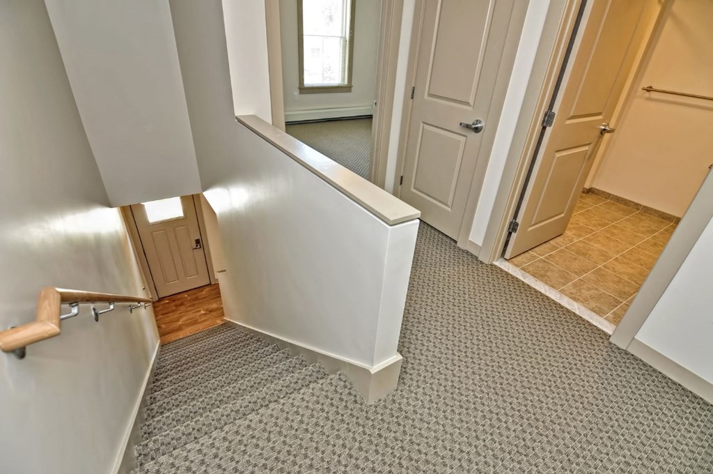 a small hallway with a door to a bathroom and a hall way with a sink