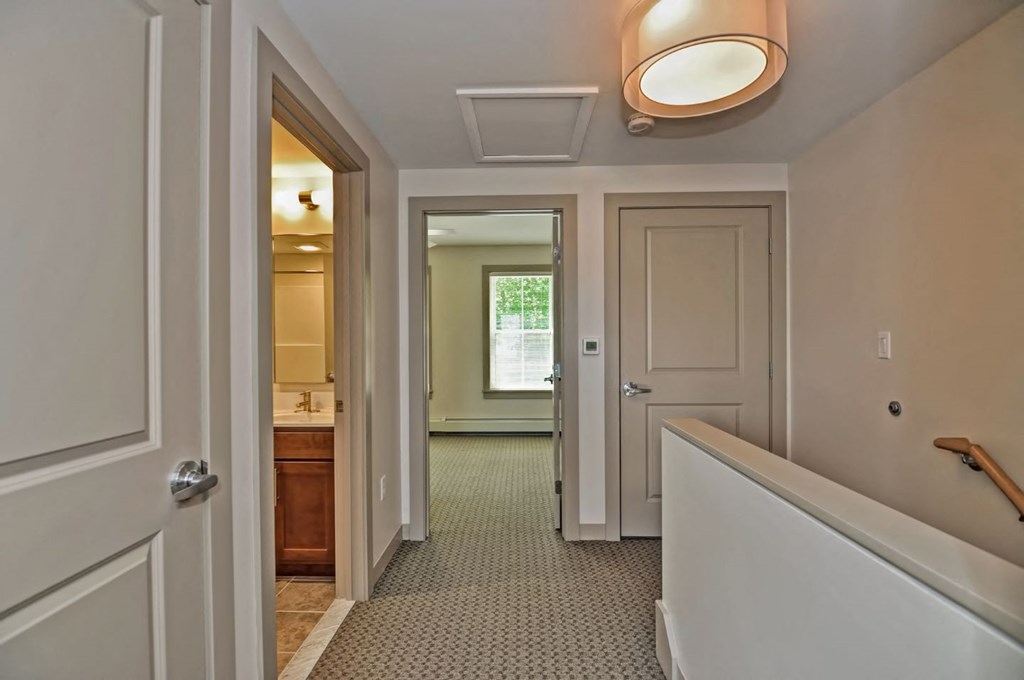 a hallway with a staircase and a door to a bathroom