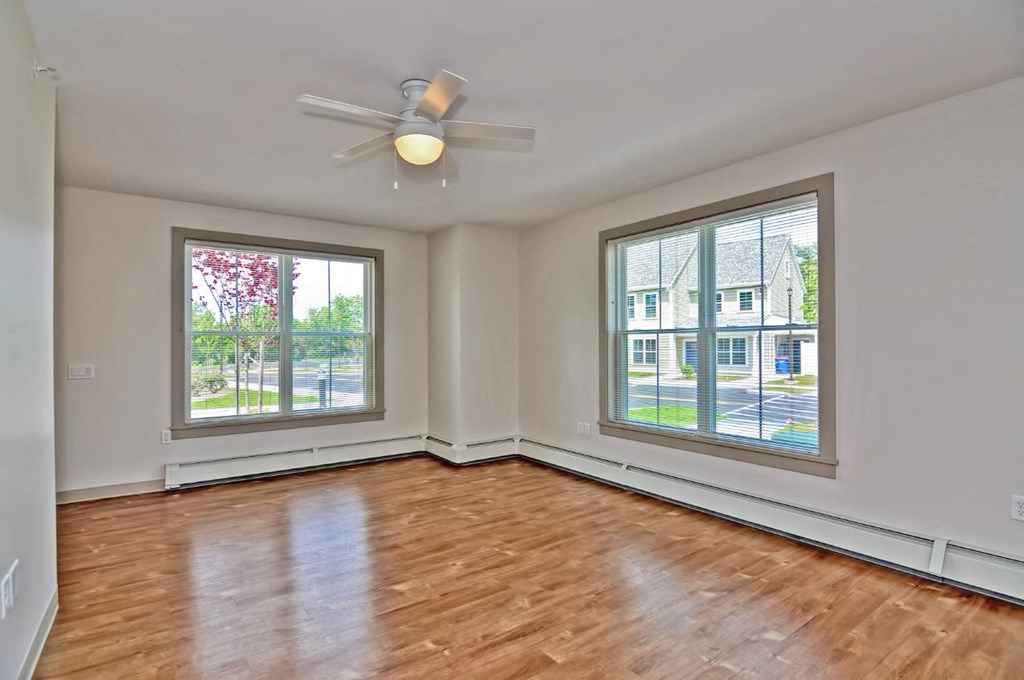 an empty living room with a ceiling fan and two windows