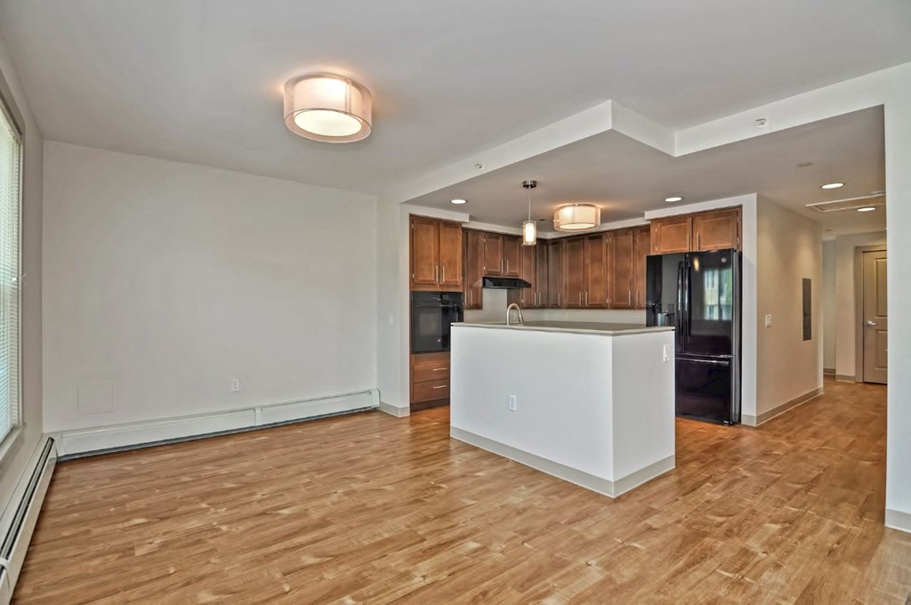 an empty living room with a kitchen with a large island