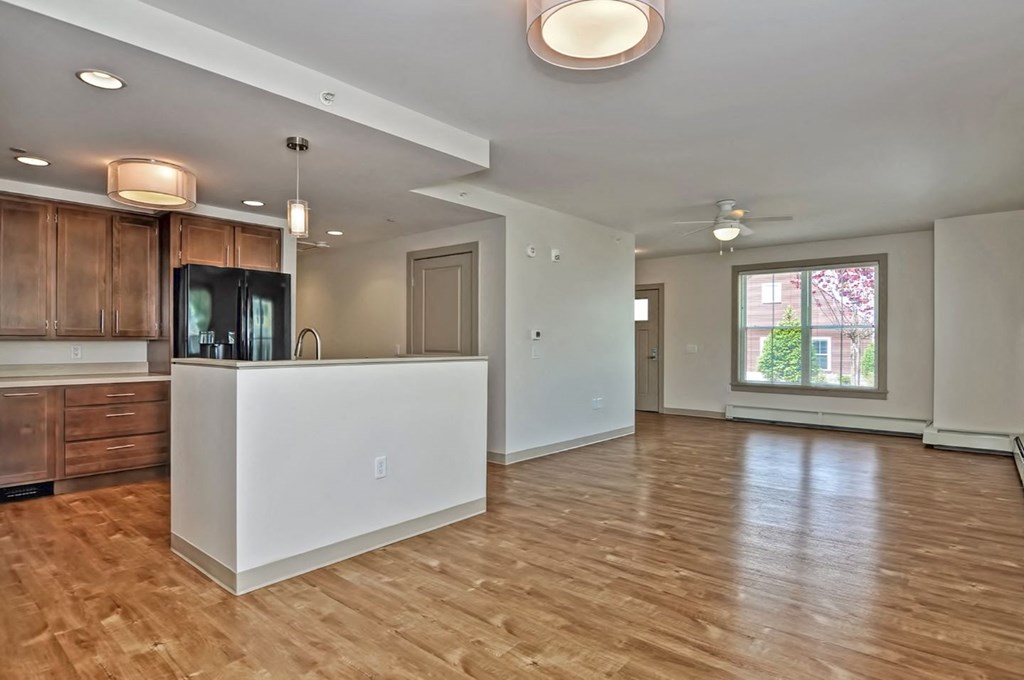 an open kitchen and living room with a white island and wood floors