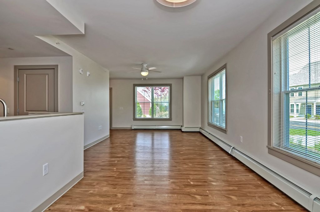 an empty living room with a large window and a kitchen