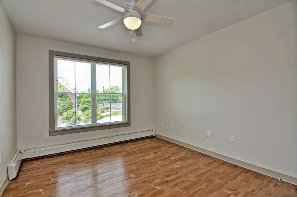 an empty living room with a window and a ceiling fan
