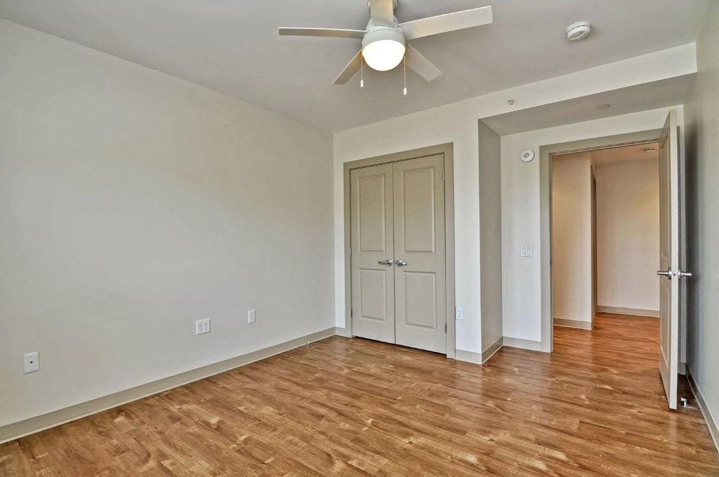 an empty living room with a ceiling fan and a door to a closet