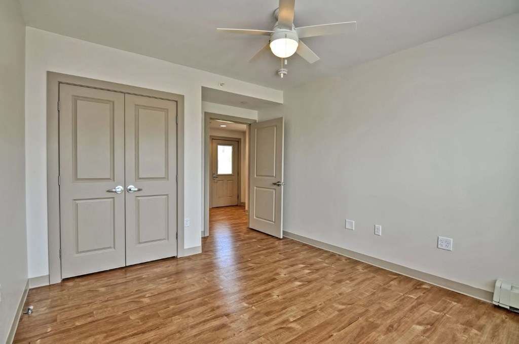 an empty living room with white walls and a ceiling fan