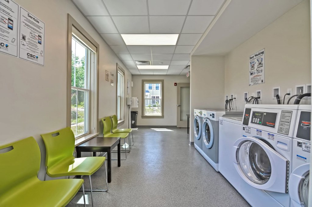 a laundry room with washers and dryers and green chairs