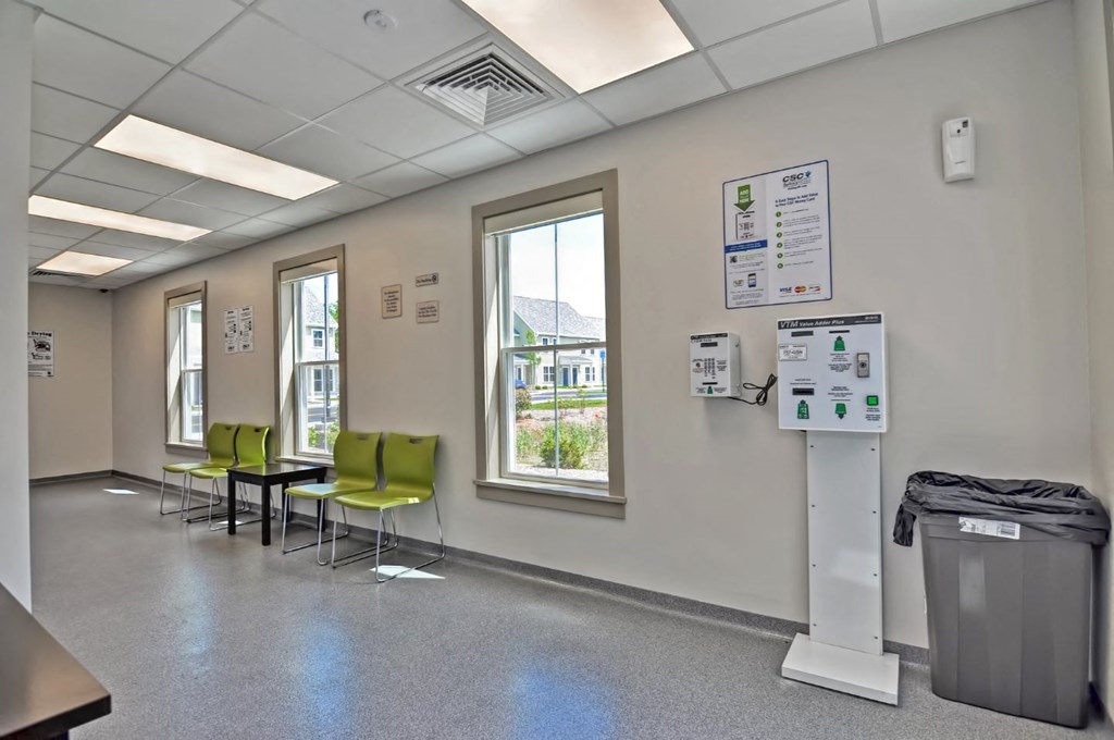a waiting room in a hospital with green chairs and a sink