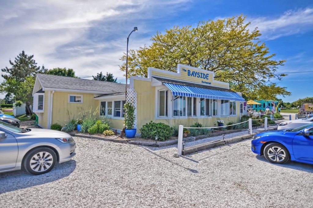 a parking lot in front of a yellow building with cars parked