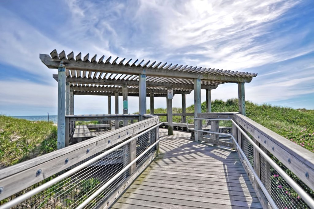 a boardwalk leading to a beach with a pergola