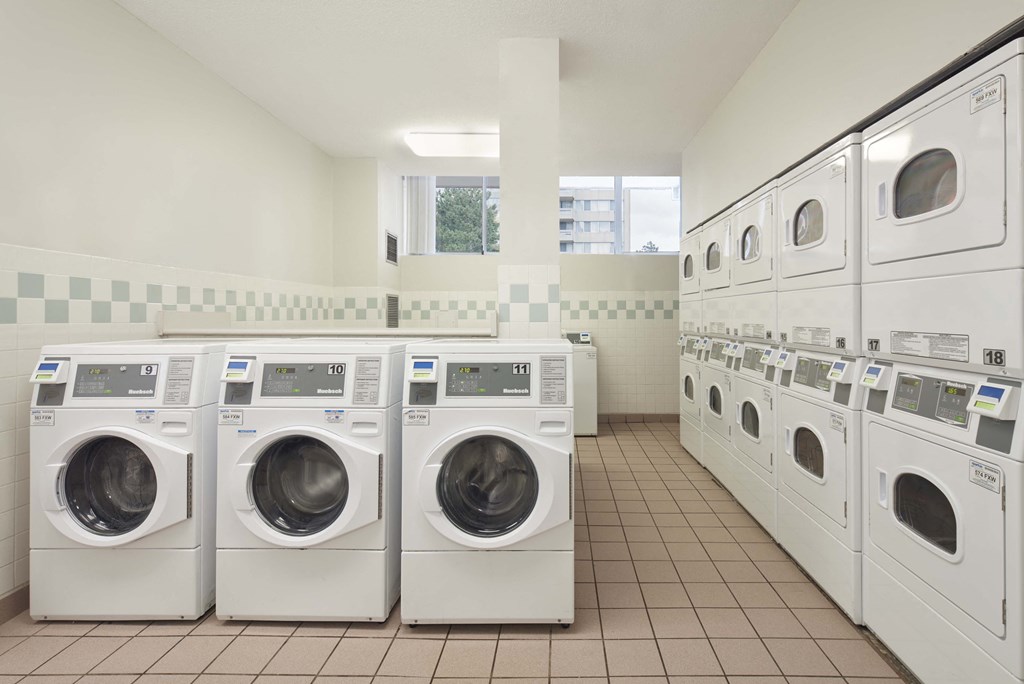 a row of washers and dryers in a laundry room with many washing machines