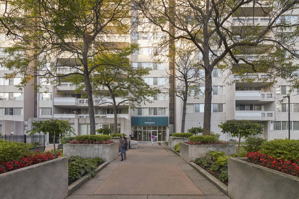 person walking down a path in front of an apartment building