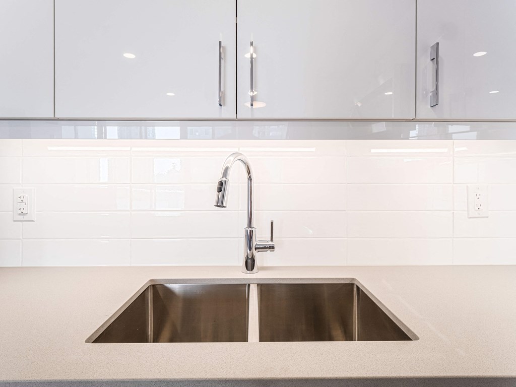 a stainless steel sink in a kitchen with white tiles