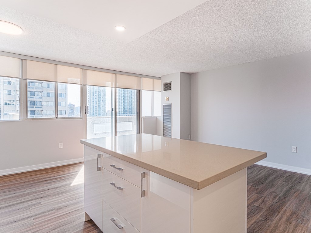 the living room and kitchen of an apartment with white cabinets and a counter top
