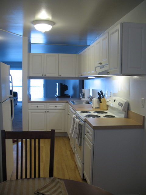 an empty kitchen with white cabinets and a table