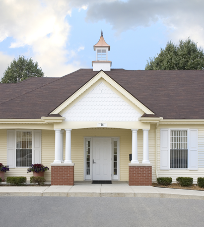 the front of a yellow house with white pillars and a white door