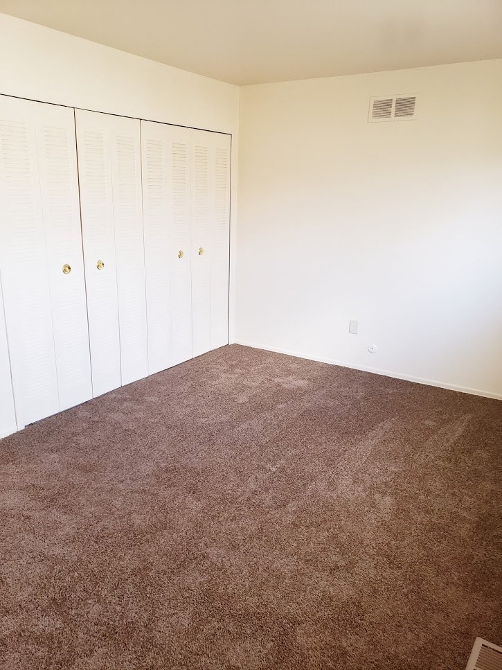 a carpeted room with white closets on the wall