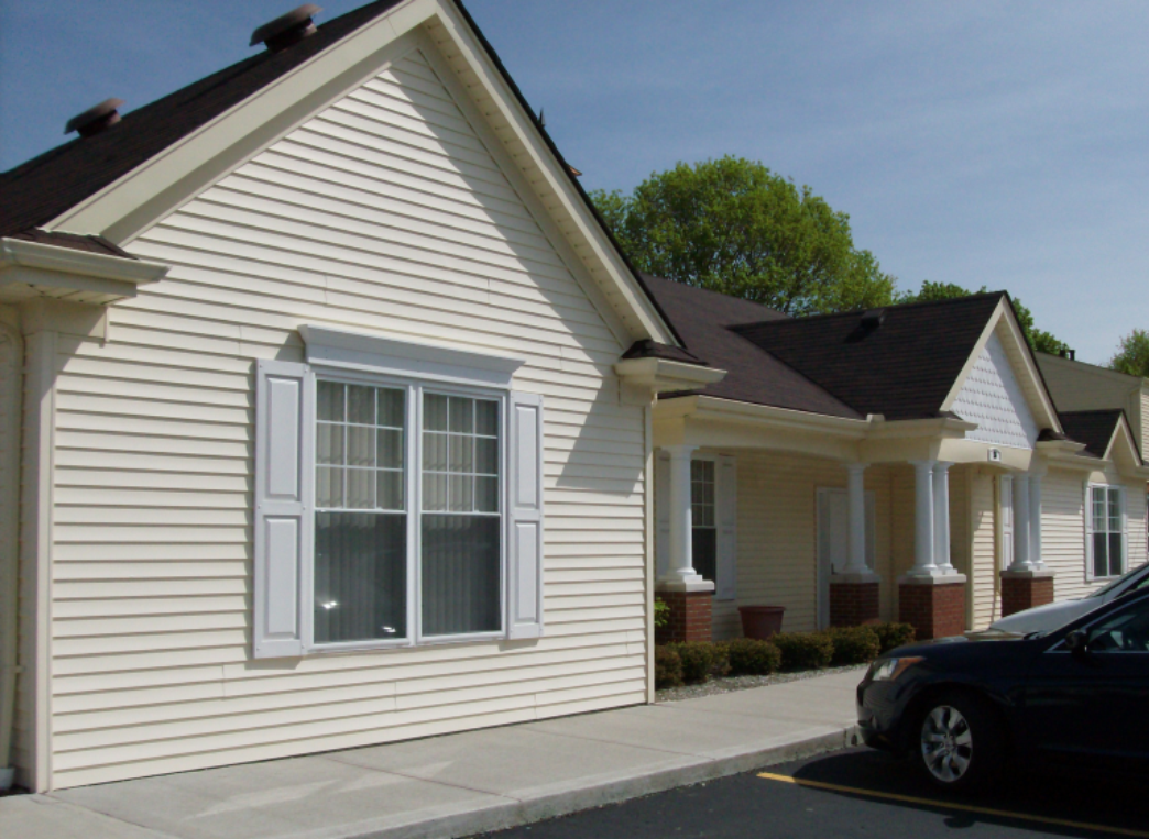a white house with white shutters and a black car parked outside