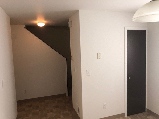an empty living room with a door to a staircase