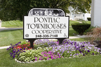 a sign townhouses cooperative in front of a garden