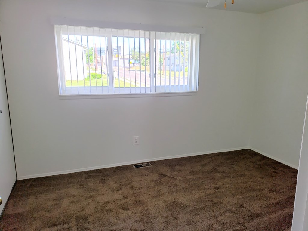 an empty room with a window and carpet