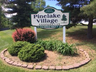 a sign for the pine lake village cooperative in the middle of a garden