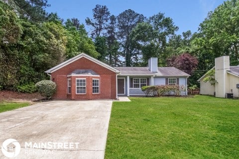 a small brick house with a lawn and a driveway