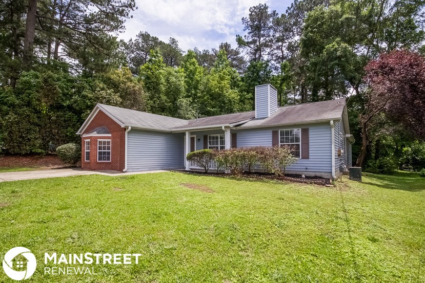 a blue house with a green lawn and trees