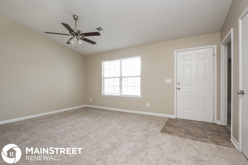 an empty living room with a ceiling fan and a white door
