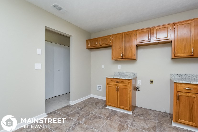 a kitchen with wooden cabinets and tile floors and a door to a closet