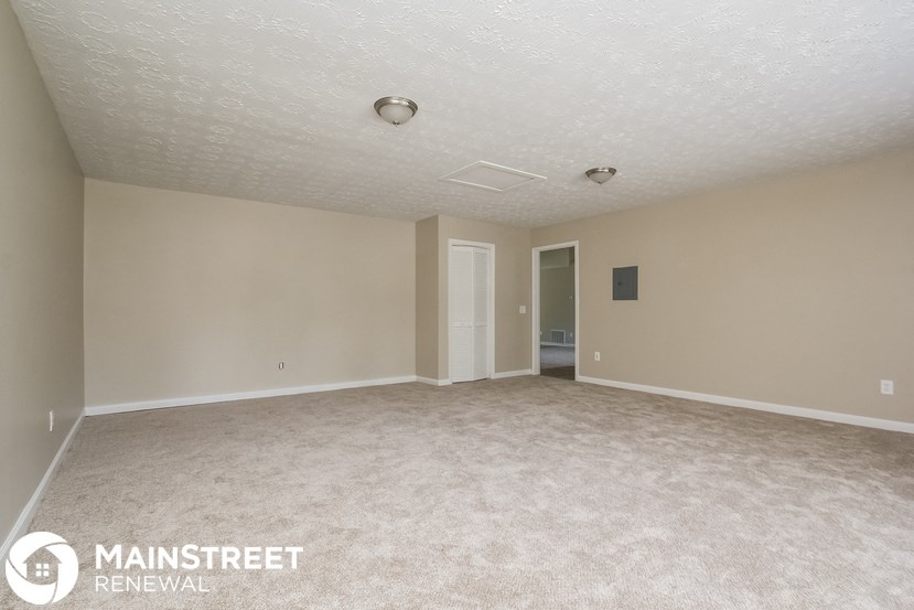 an empty living room with carpet and a door to a bathroom