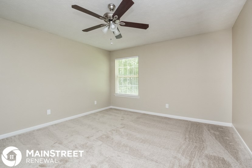 the master bedroom has a carpeted floor and a ceiling fan
