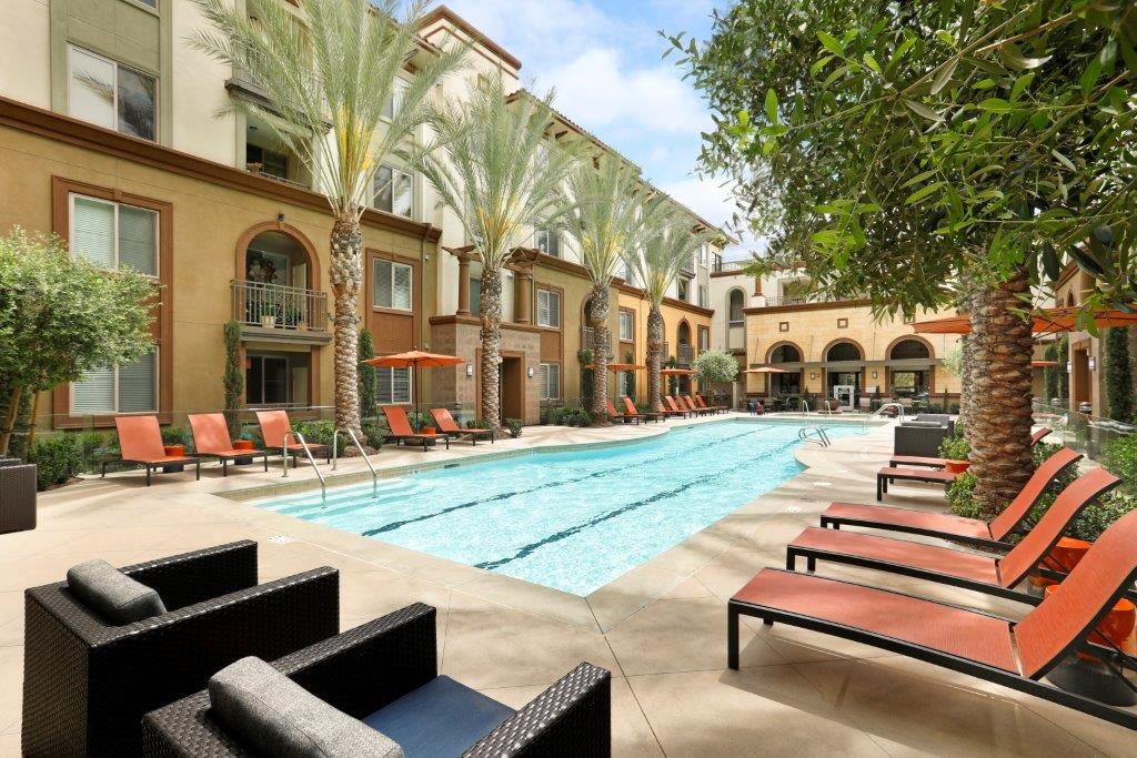 a swimming pool with lounge chairs and trees in front of a building