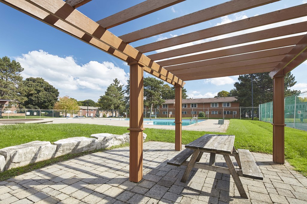 a picnic area with a picnic table in front of a pool