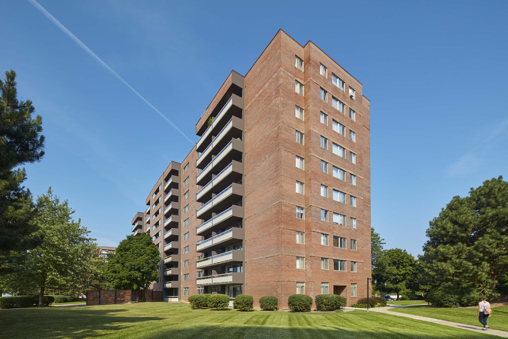 a tall brick building with grass and trees