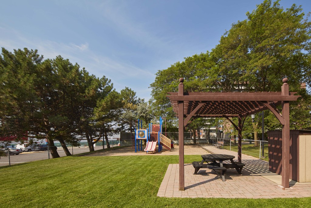 a picnic area with a picnic table and a playground in a park