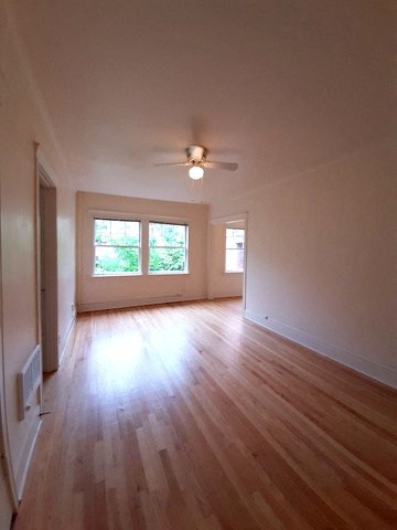 an empty living room with a ceiling fan and wood floors