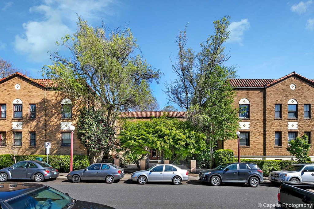 a row of brick apartment buildings with cars parked in front