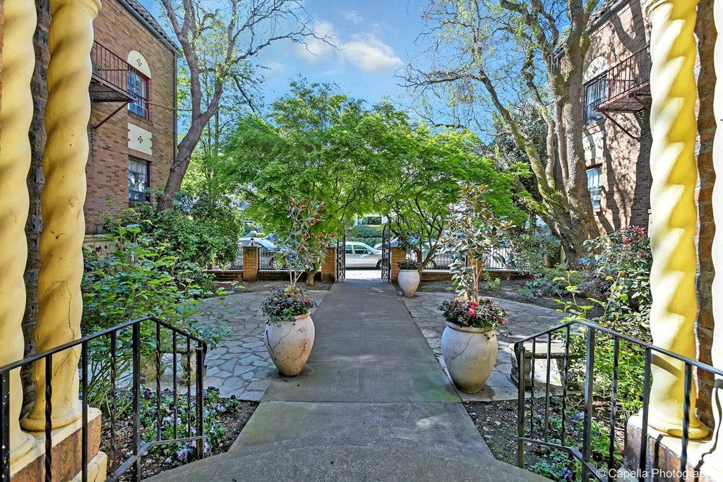 a pathway with vases and trees in front of a building