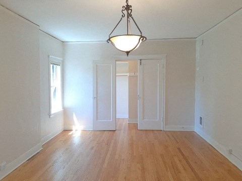 an empty living room with white walls and a chandelier